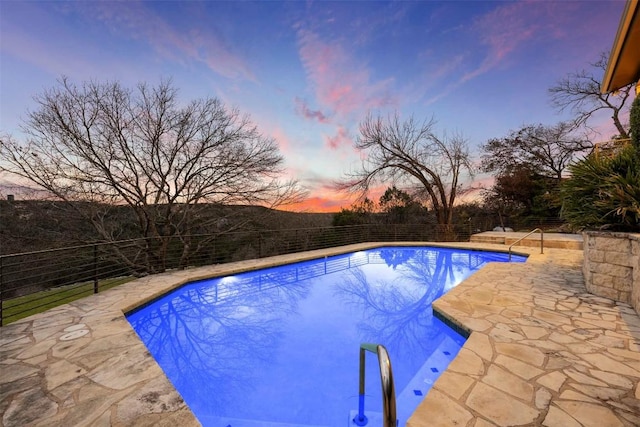 pool at dusk featuring a patio, fence, and a fenced in pool