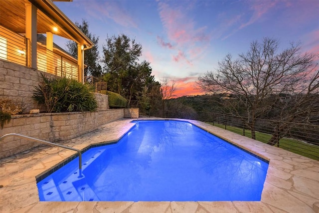 pool at dusk with a fenced in pool and a fenced backyard