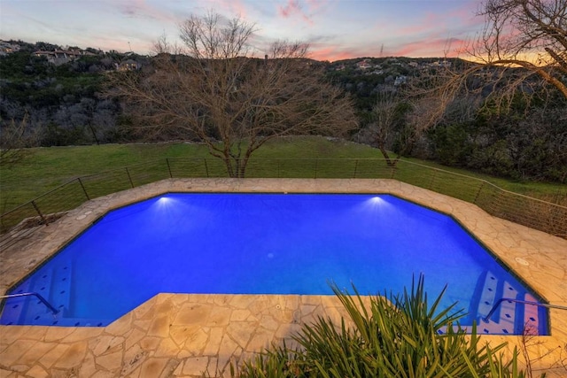 pool at dusk with a fenced in pool, a fenced backyard, and a yard