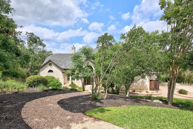 view of front of house with stone siding and a chimney