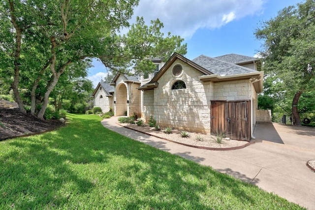 view of front of home featuring a shingled roof, a front lawn, and stone siding