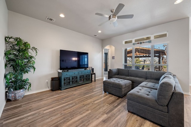 living area with arched walkways, recessed lighting, wood finished floors, visible vents, and baseboards