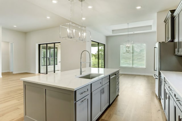 kitchen featuring a raised ceiling, gray cabinets, stainless steel appliances, a sink, and recessed lighting