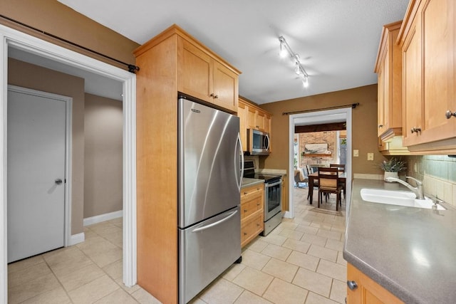 kitchen with light tile patterned flooring, light brown cabinets, a sink, appliances with stainless steel finishes, and decorative backsplash