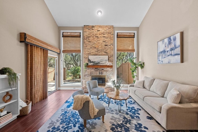 living room featuring lofted ceiling, a brick fireplace, a wealth of natural light, and wood finished floors