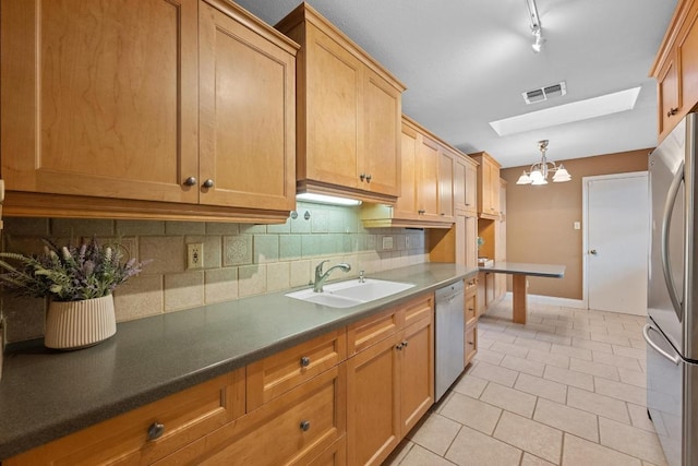 kitchen featuring a skylight, stainless steel appliances, visible vents, decorative backsplash, and a sink