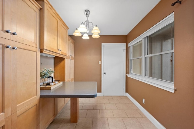 kitchen with hanging light fixtures, an inviting chandelier, light brown cabinets, light tile patterned flooring, and baseboards