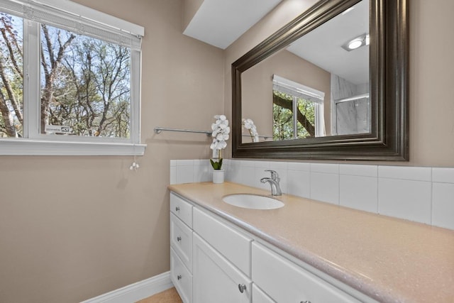 bathroom with a shower with door, baseboards, backsplash, and vanity