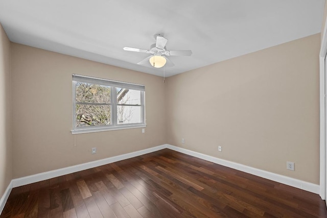 unfurnished room with dark wood-type flooring, a ceiling fan, and baseboards