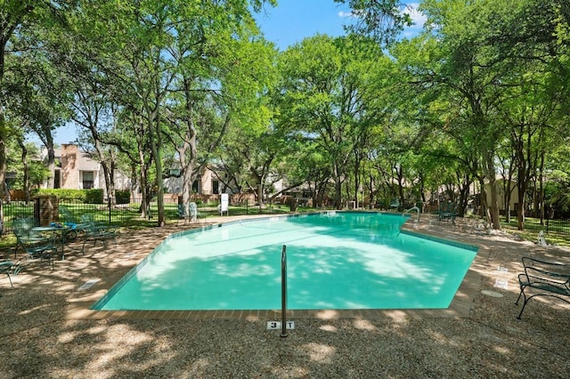 community pool with a patio and fence