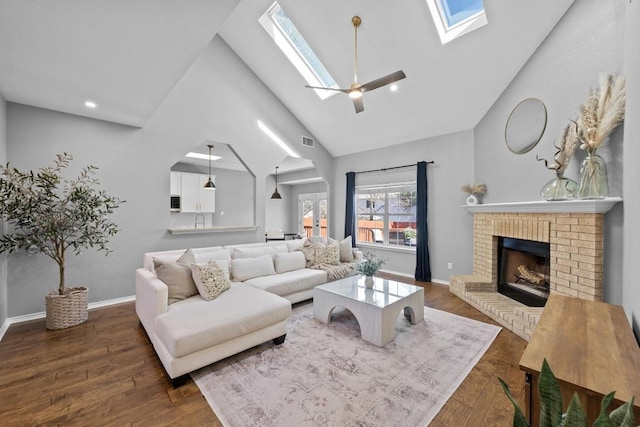 living room featuring high vaulted ceiling, a fireplace, a skylight, visible vents, and dark wood finished floors