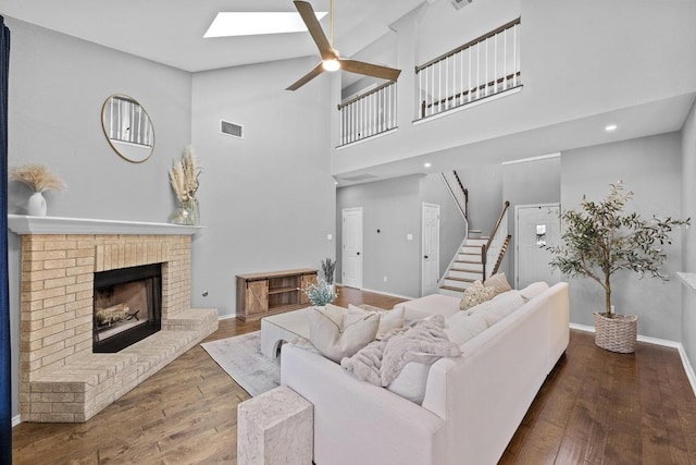 living room featuring hardwood / wood-style flooring, a fireplace, a skylight, and visible vents