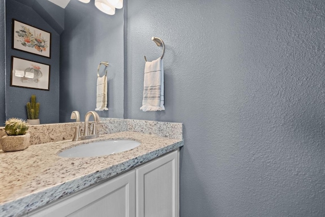 bathroom with a textured wall and vanity