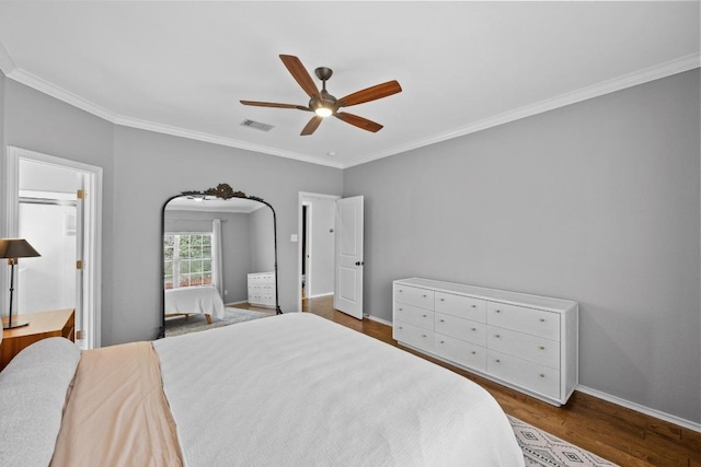 bedroom with visible vents, baseboards, crown molding, and wood finished floors