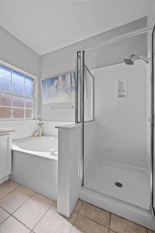 bathroom featuring a stall shower, tile patterned flooring, and a bath