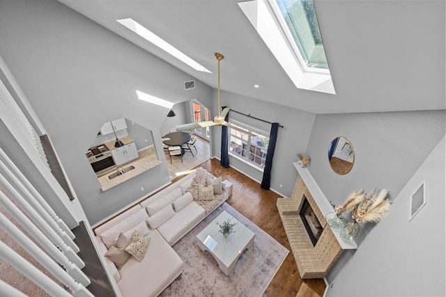 living room featuring lofted ceiling with skylight, visible vents, and wood finished floors