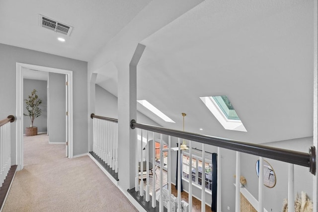 corridor with vaulted ceiling with skylight, baseboards, visible vents, and carpet flooring