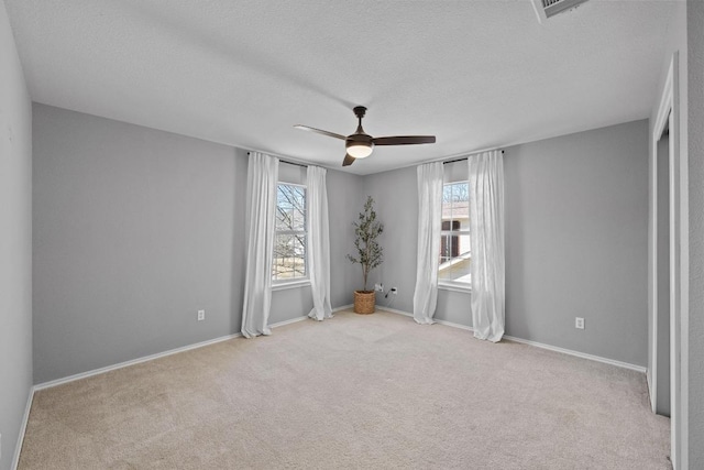 spare room with carpet floors, a textured ceiling, baseboards, and a ceiling fan