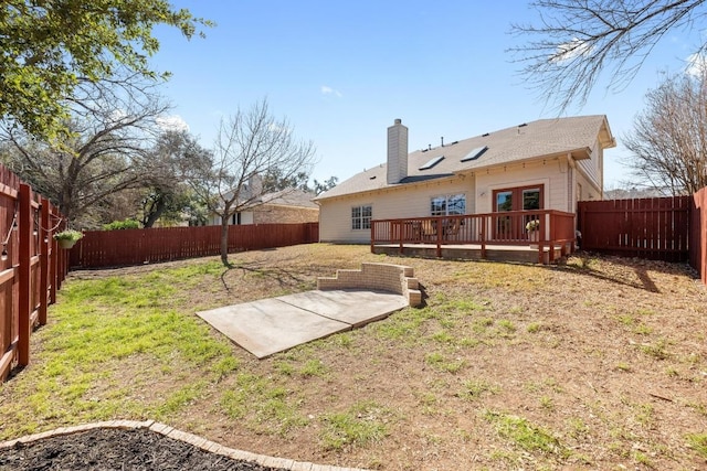 rear view of house featuring french doors, a chimney, a lawn, a fenced backyard, and a wooden deck