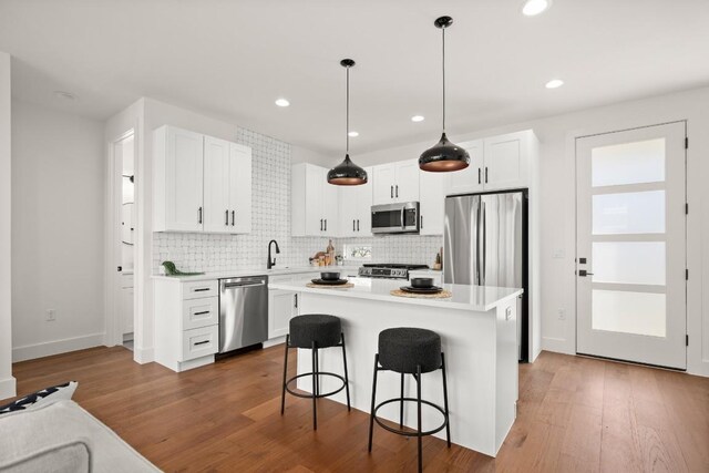 kitchen featuring stainless steel appliances, tasteful backsplash, a kitchen breakfast bar, light countertops, and recessed lighting