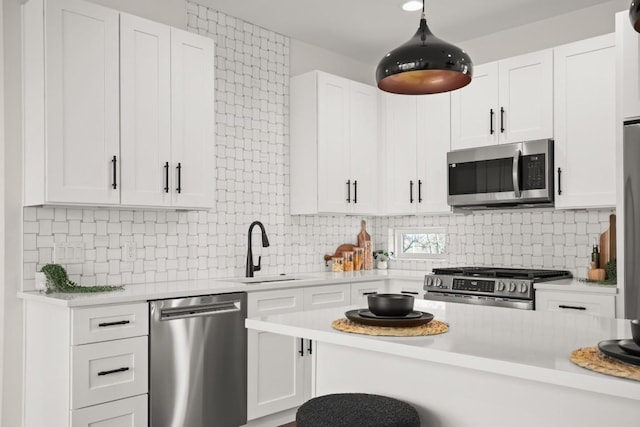 kitchen with stainless steel appliances, light countertops, a sink, and white cabinetry