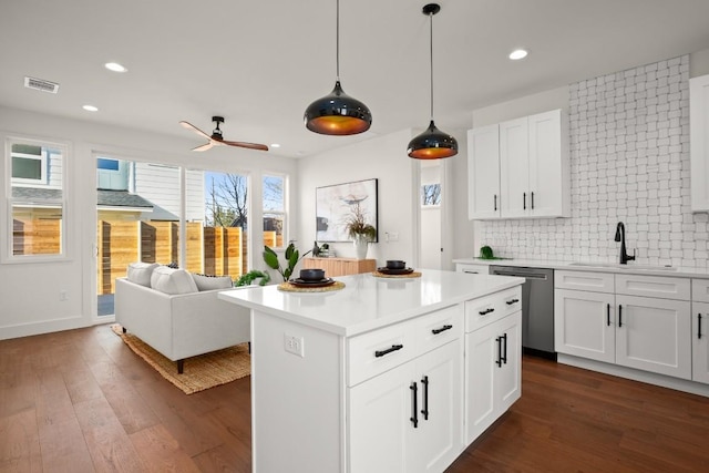 kitchen with stainless steel dishwasher, a sink, decorative backsplash, a ceiling fan, and light countertops