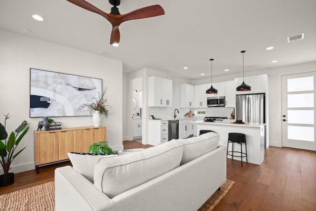 living area featuring wood finished floors, baseboards, recessed lighting, and a ceiling fan