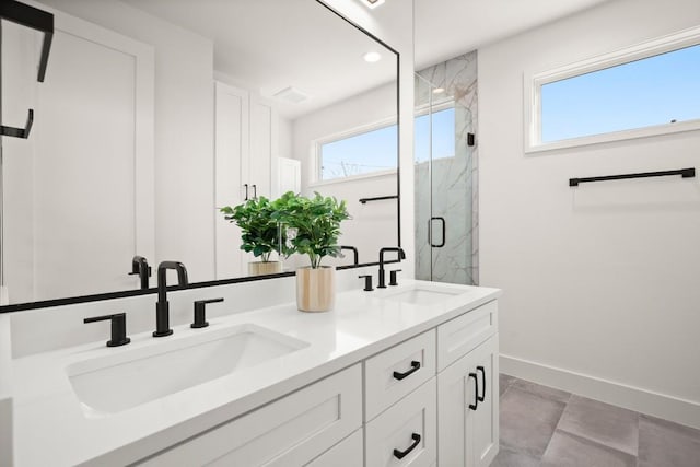 full bath with healthy amount of natural light, baseboards, a marble finish shower, double vanity, and recessed lighting