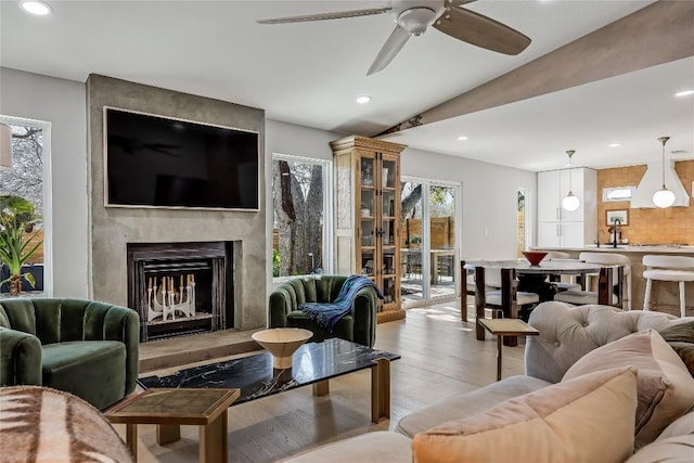 living area with recessed lighting, vaulted ceiling, a premium fireplace, and wood finished floors