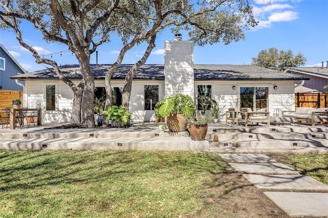 back of house featuring a patio, a lawn, a chimney, and fence