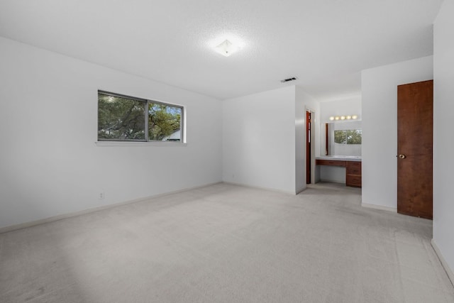 spare room with visible vents, built in study area, light carpet, and baseboards