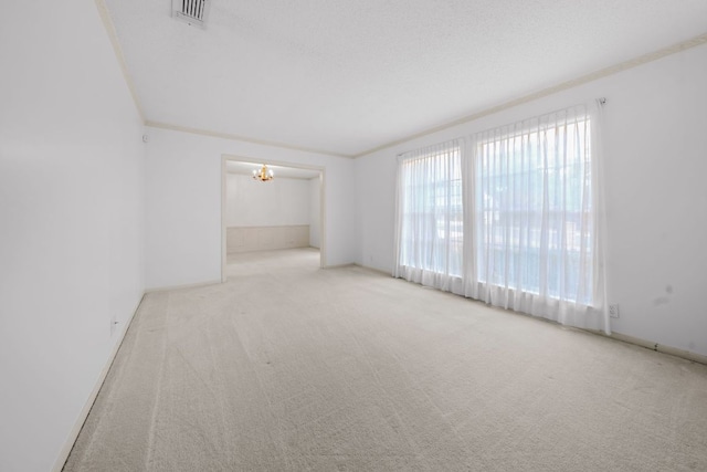 empty room featuring ornamental molding, carpet flooring, visible vents, and an inviting chandelier