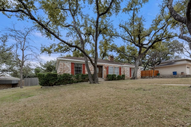 view of front of house featuring fence, a chimney, and a front lawn