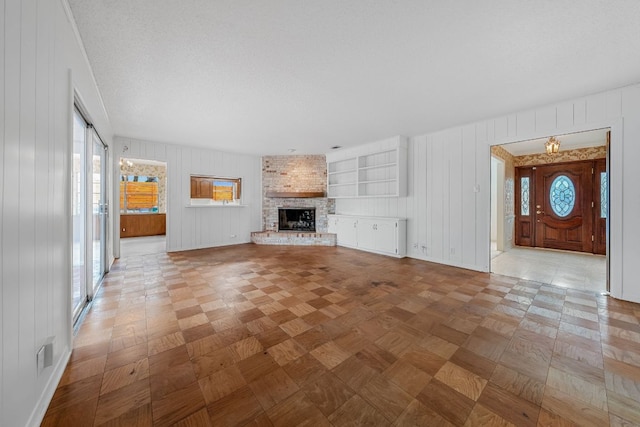 unfurnished living room featuring baseboards, a textured ceiling, a fireplace, and a healthy amount of sunlight