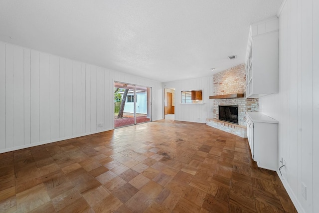 unfurnished living room featuring a fireplace, visible vents, and a textured ceiling