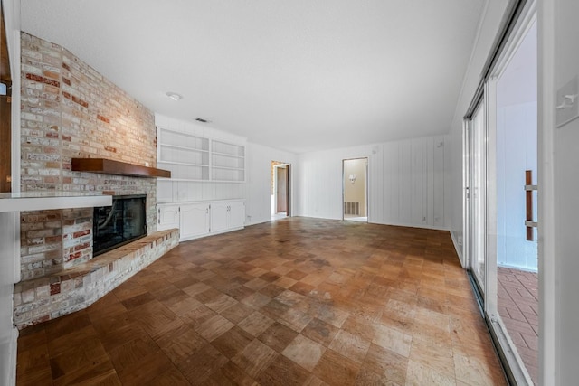 unfurnished living room featuring a brick fireplace and visible vents