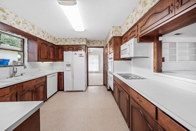 kitchen with a textured ceiling, white appliances, a sink, light floors, and wallpapered walls