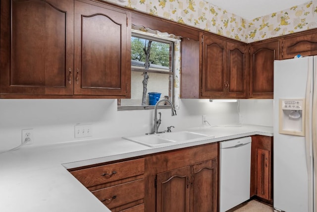 kitchen with white appliances, light countertops, a sink, and wallpapered walls