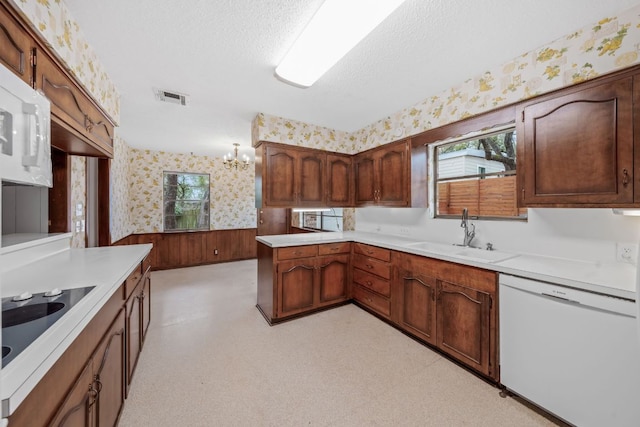 kitchen featuring a wainscoted wall, light floors, a sink, white appliances, and wallpapered walls