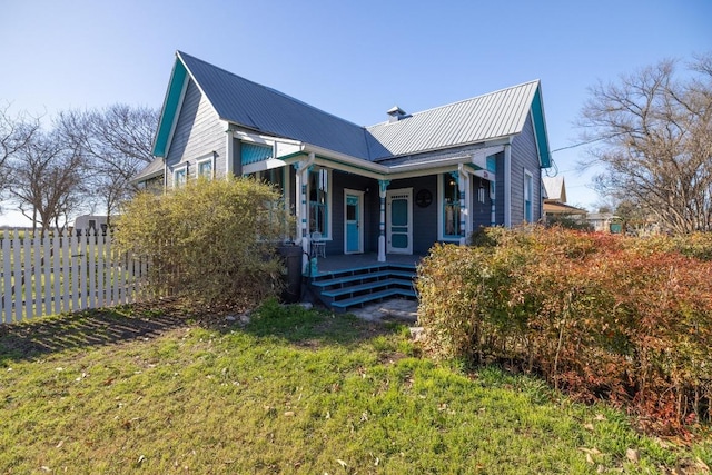 view of front facade featuring a porch, metal roof, and fence