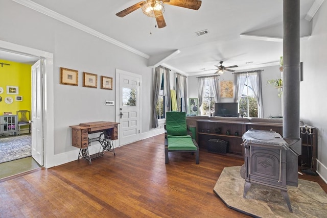 sitting room with ornamental molding, a wood stove, visible vents, and wood finished floors