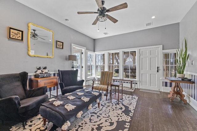 living area with a ceiling fan, baseboards, visible vents, and hardwood / wood-style floors