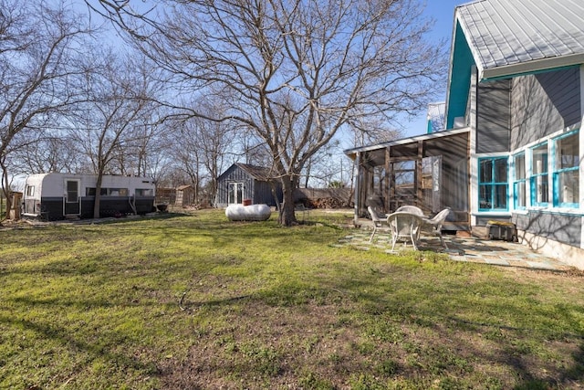 view of yard with a sunroom, a patio area, an outdoor structure, and a storage unit