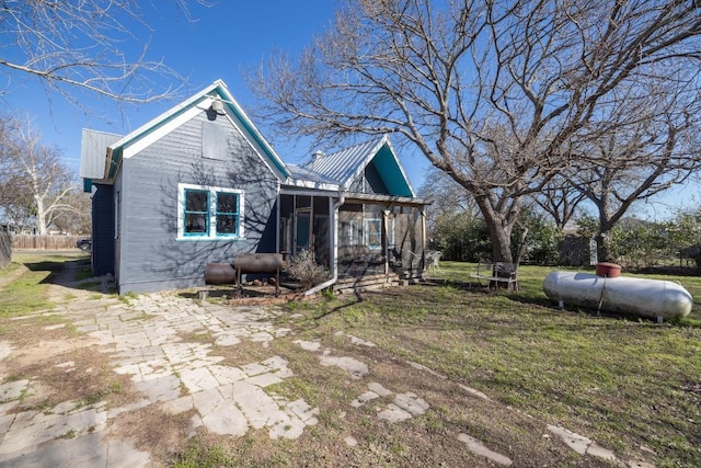 view of front of home with metal roof, a front yard, a sunroom, and heating fuel