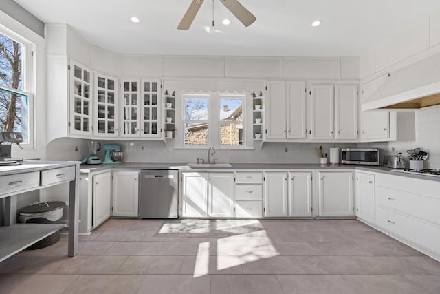 kitchen with tasteful backsplash, appliances with stainless steel finishes, white cabinetry, open shelves, and a sink