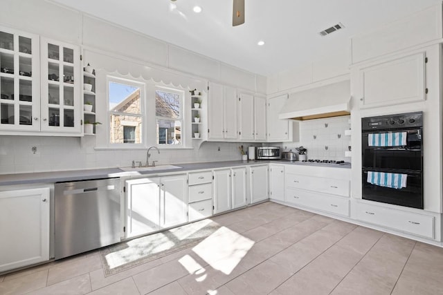 kitchen featuring visible vents, decorative backsplash, appliances with stainless steel finishes, premium range hood, and a sink