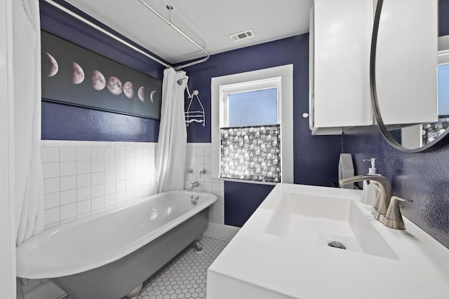 full bathroom featuring a washtub, visible vents, a textured wall, vanity, and tile patterned floors