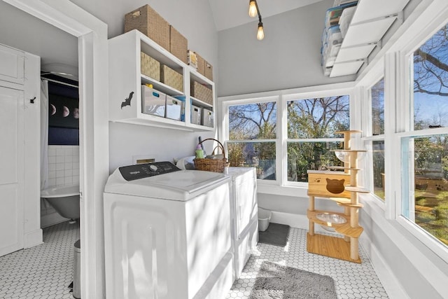 clothes washing area with laundry area, washing machine and dryer, baseboards, and tile patterned floors