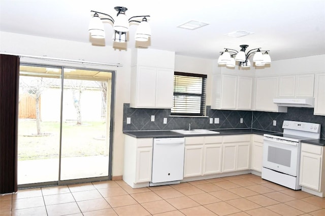 kitchen featuring a chandelier, under cabinet range hood, white appliances, a sink, and dark countertops