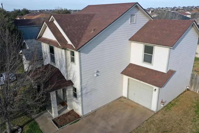 exterior space with a garage, a shingled roof, and concrete driveway